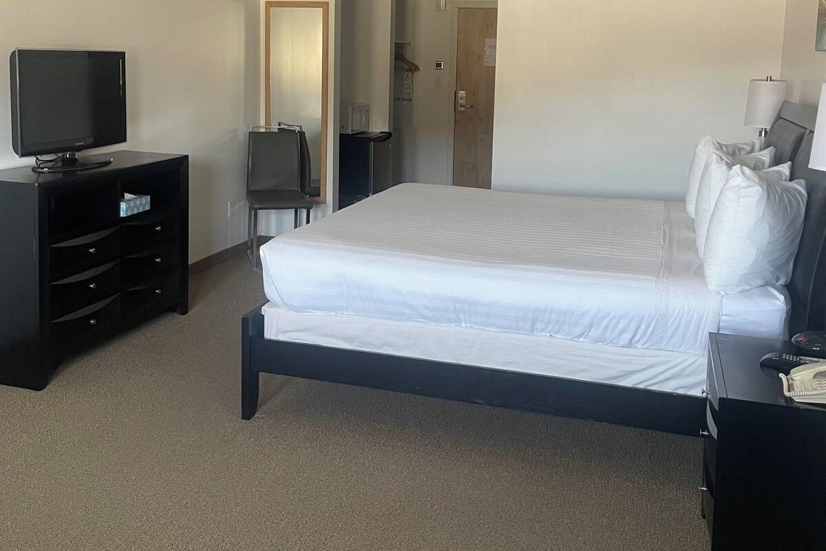 A hotel room with a bed, a TV, a desk, and a chair.