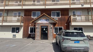 A two-story building with a sign for Sunshine Inn, a parking lot, and a parked SUV. - Sunshine Inn Houston  (Houston)