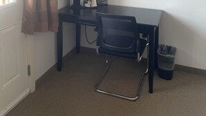 A small, simple room with a desk, chair, and a trash bin. - Sunshine Inn Houston  (Houston)