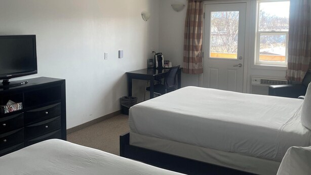 A hotel room with two beds, a desk with a chair, a television, and a window with curtains. - Sunshine Inn Houston  (Houston)