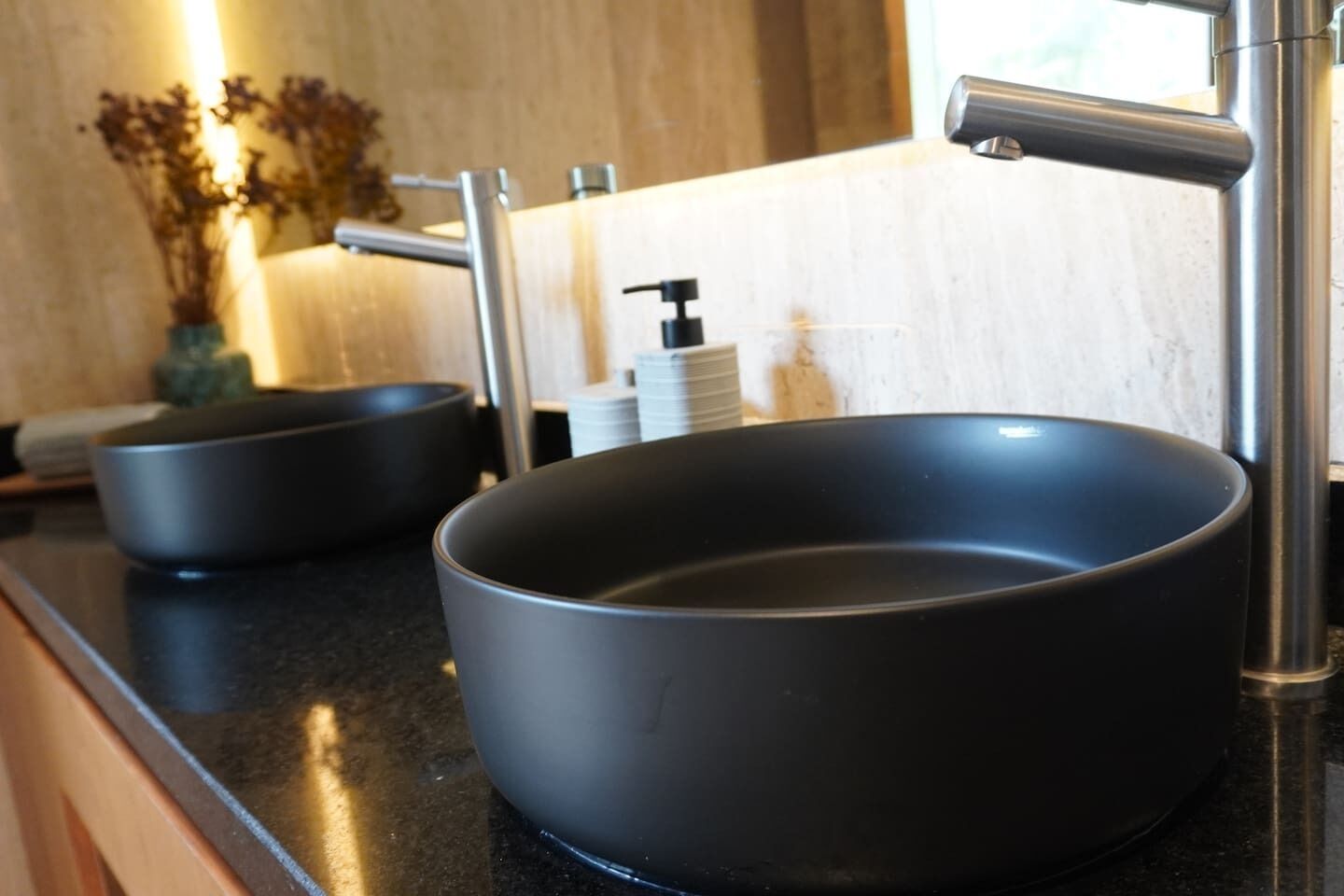 Une salle de bain moderne avec un lavabo noir, un robinet et un miroir.
