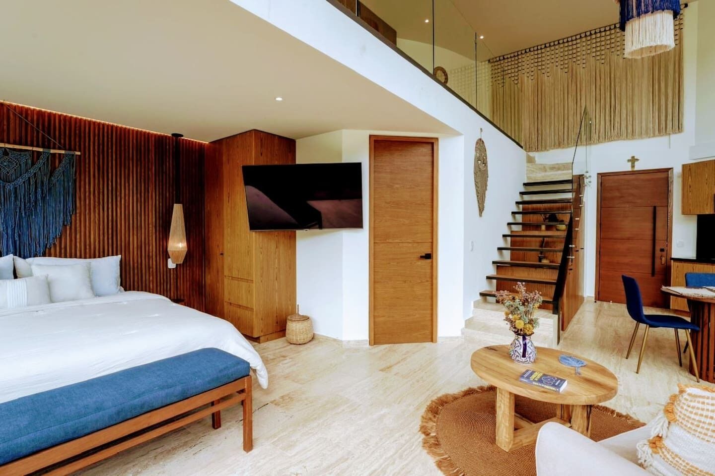 Une chambre d’hôtel moderne équipée d’un lit, d’une télévision, d’un escalier et d’un coin repas.