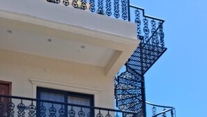 A multi-story building with a spiral staircase, outdoor seating area with chairs and tables, and a checkered floor pattern. - KAY'S EDEN (Mahabalipuram)