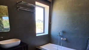 A modern bathroom with a freestanding bathtub, a vessel sink, and a window providing natural light. - KAY'S EDEN (Mahabalipuram)