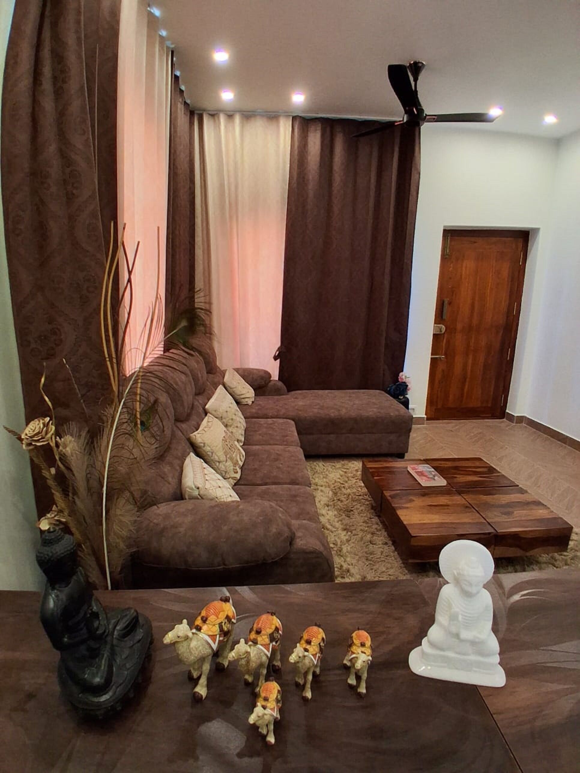 A living room with a sectional sofa, a coffee table, decorative items, and a door.