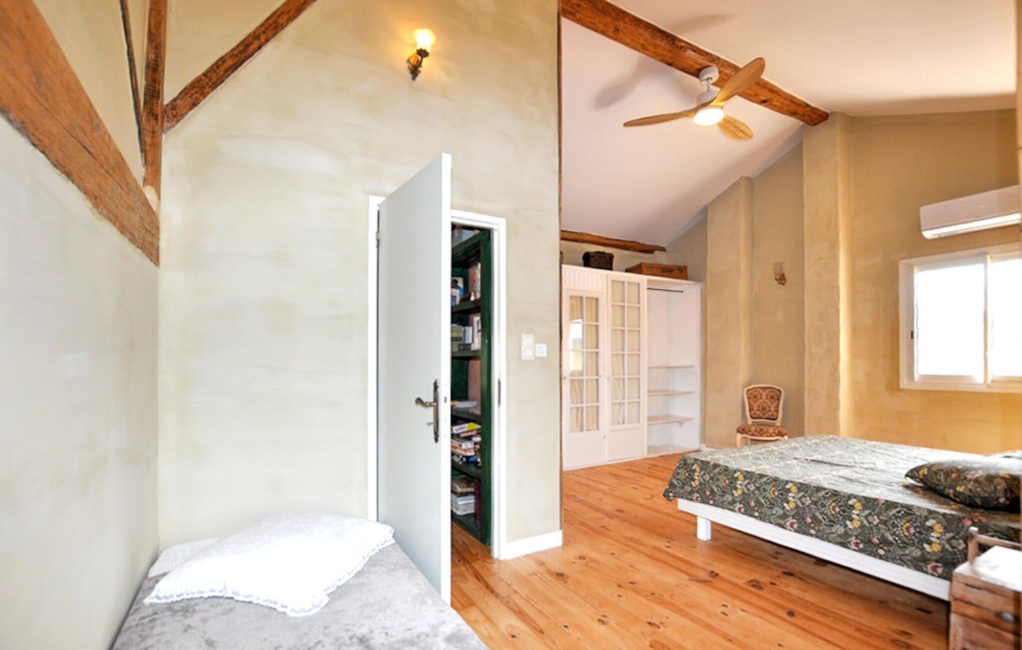 Une chambre à coucher avec un lit, une armoire, une chaise et un ventilateur de plafond.