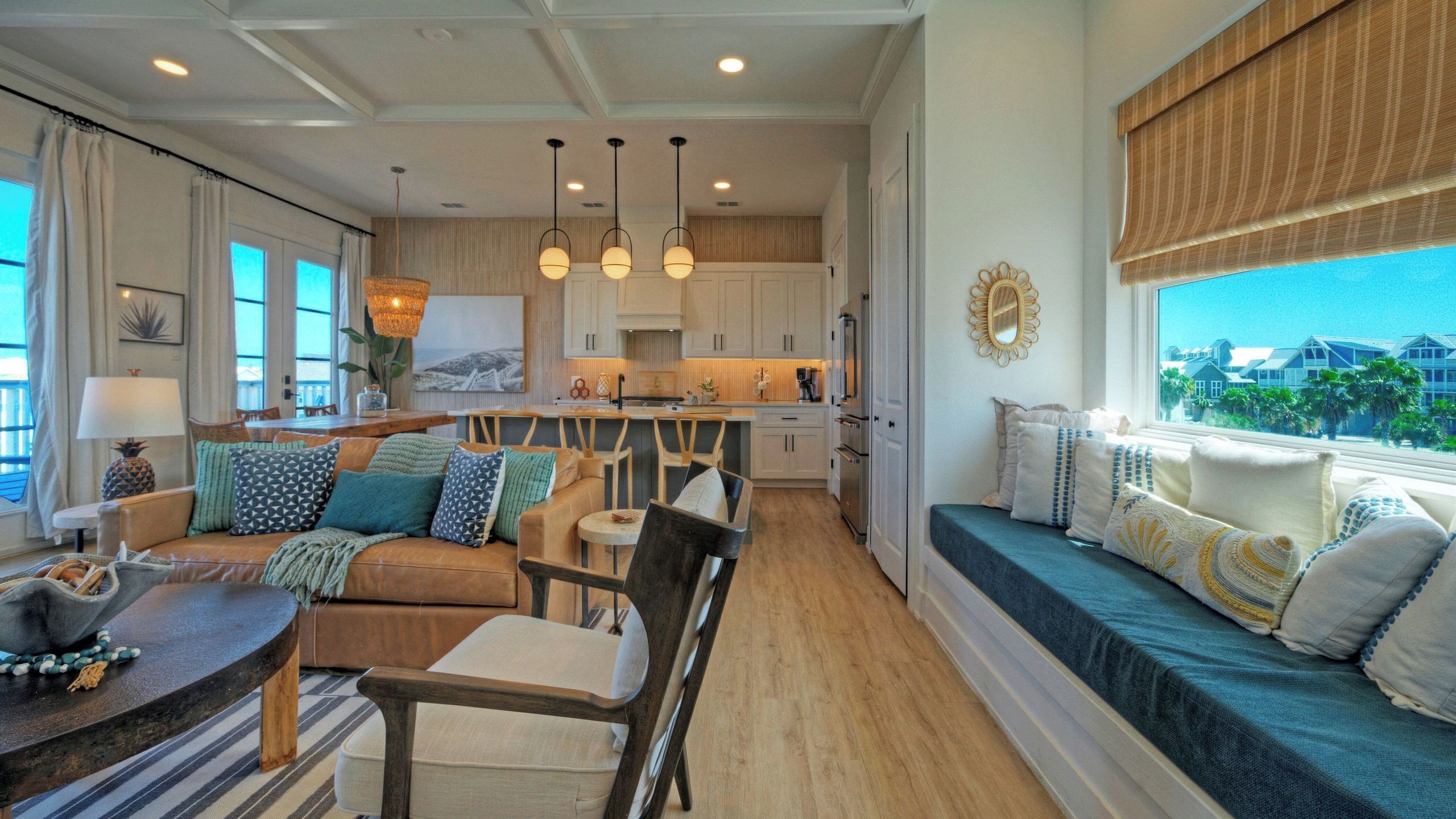 A spacious living area with a sofa, dining table, and a view of the kitchen and outside.