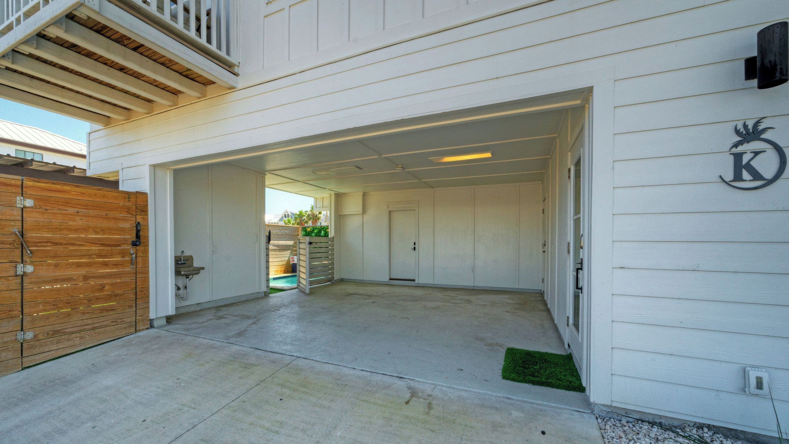 A garage with a wooden gate, a concrete floor, and a door leading to a covered area.