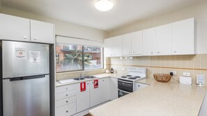 A modern kitchen with white cabinets, a stainless steel refrigerator, a gas stove, and a sink. - Sunset Reset - Bright Coastal Escape (Soldiers Point)
