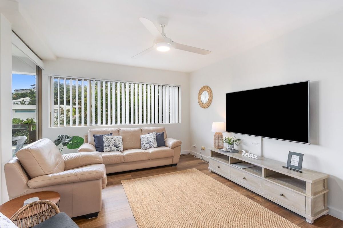 A modern living room with a sofa, TV, and a ceiling fan.