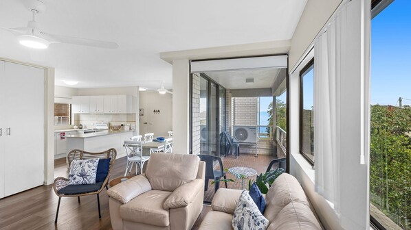 A modern living room with a sofa, chairs, and a dining area. - Sunset Reset - Bright Coastal Escape (Soldiers Point)