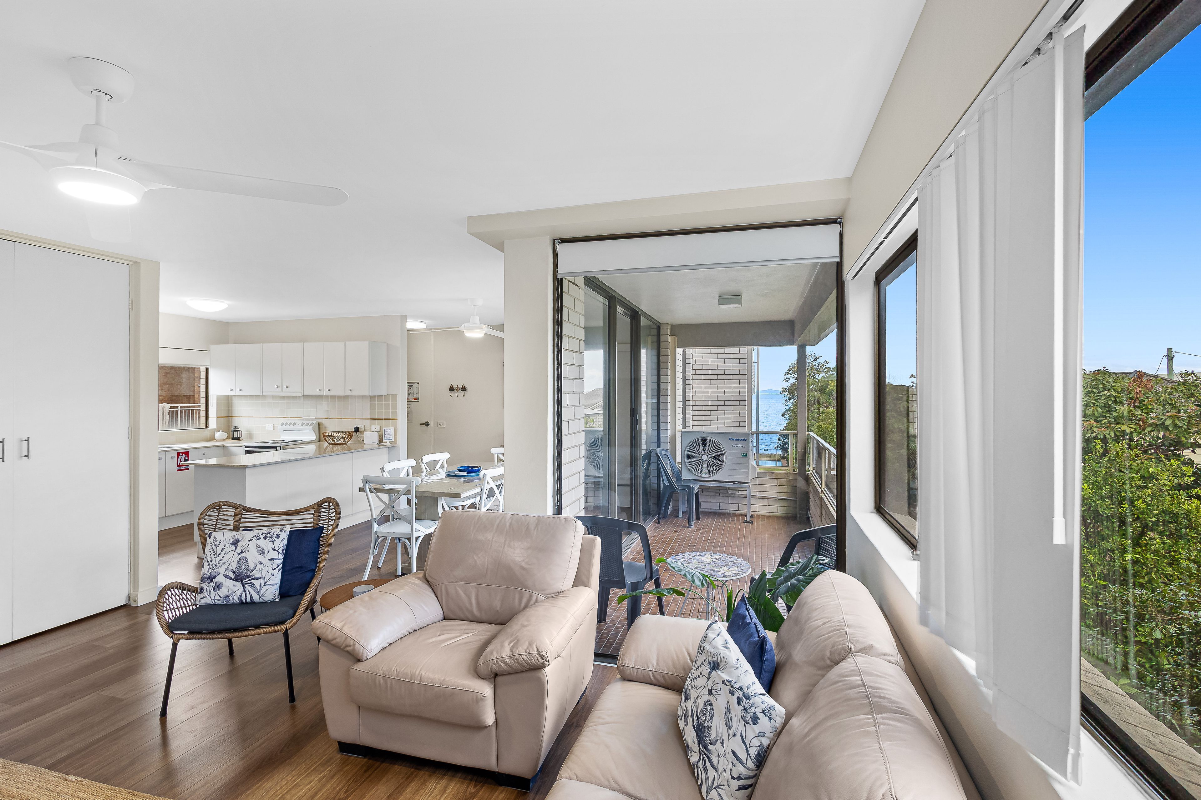 A modern living room with a sofa, chairs, and a dining area with a table and chairs.