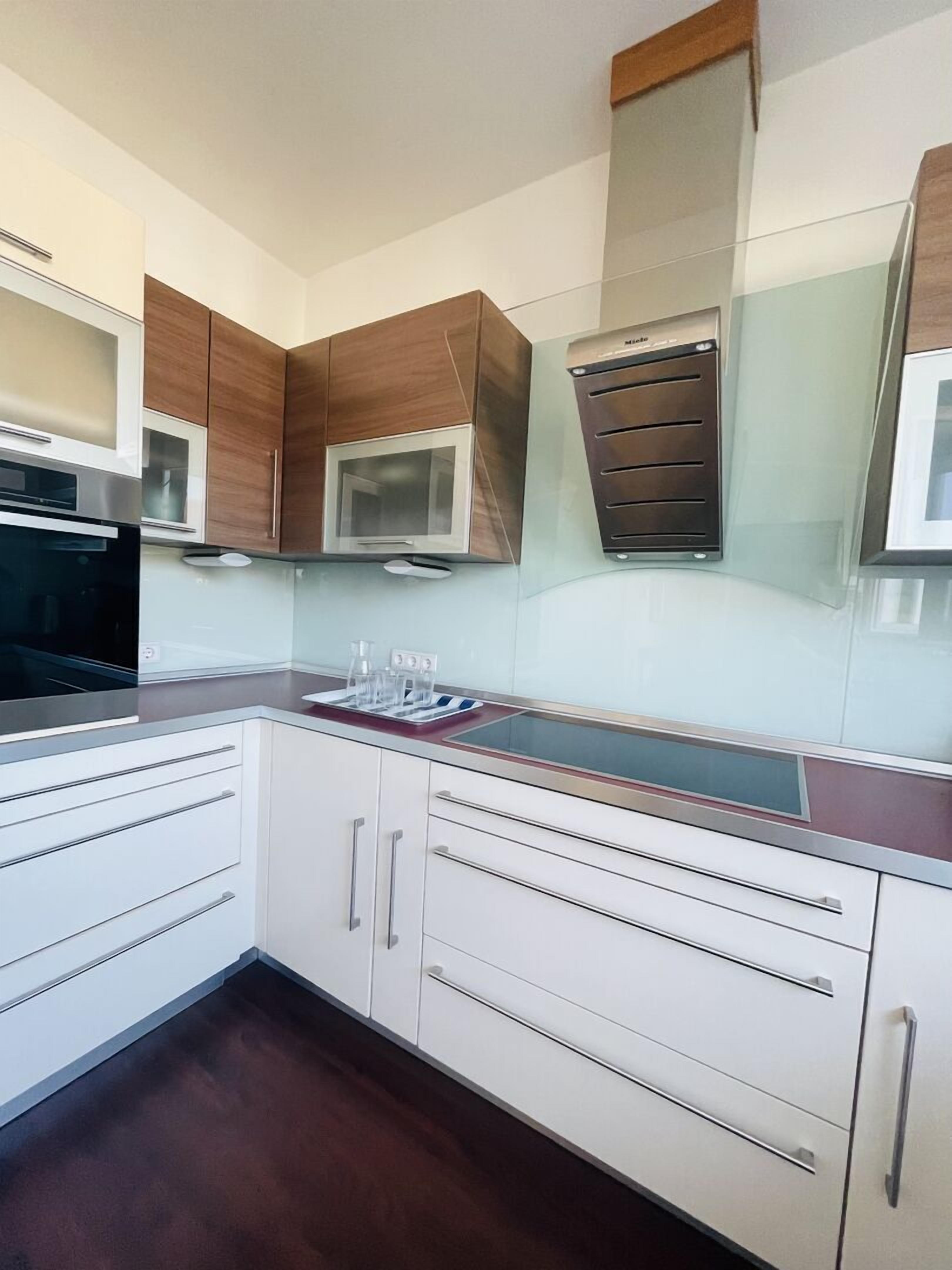 Une cuisine moderne avec des meubles blancs, un four à micro-ondes, une cuisinière et un four encastré.