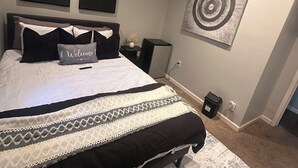 Quarto com cama, mesas de cabeceira, tapete e obras de arte nas paredes.