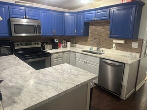 A kitchen with blue cabinets, a stainless steel microwave, a stove, and a dishwasher. - Modern Private Room Easy Access to Everything (Little Rock)