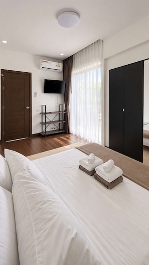 Ein Hotelzimmer mit Bett, Fernseher, Kleiderschrank und einem Fenster mit Vorhängen.
