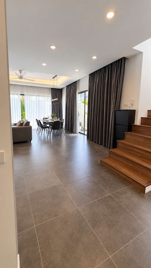A modern living space with a dining area, a staircase, and a view of the outdoors. - 2BR Pool Villa Rawai Beach Sumalee | Capital Pro (Rawai)