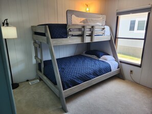 Una cama litera con ventana, una lámpara y un teclado en el suelo.