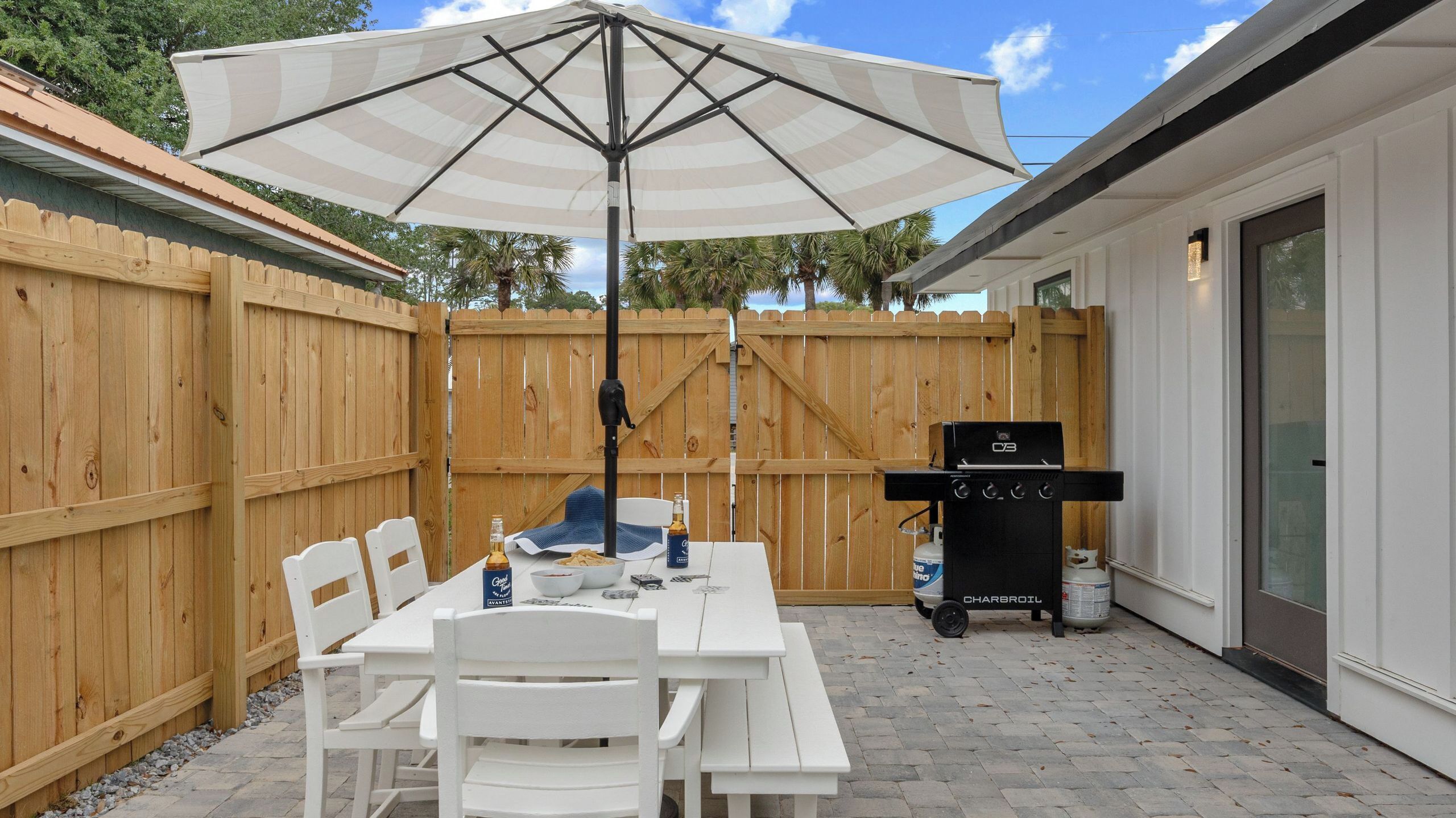 A patio with a table, chairs, a grill, and an umbrella.