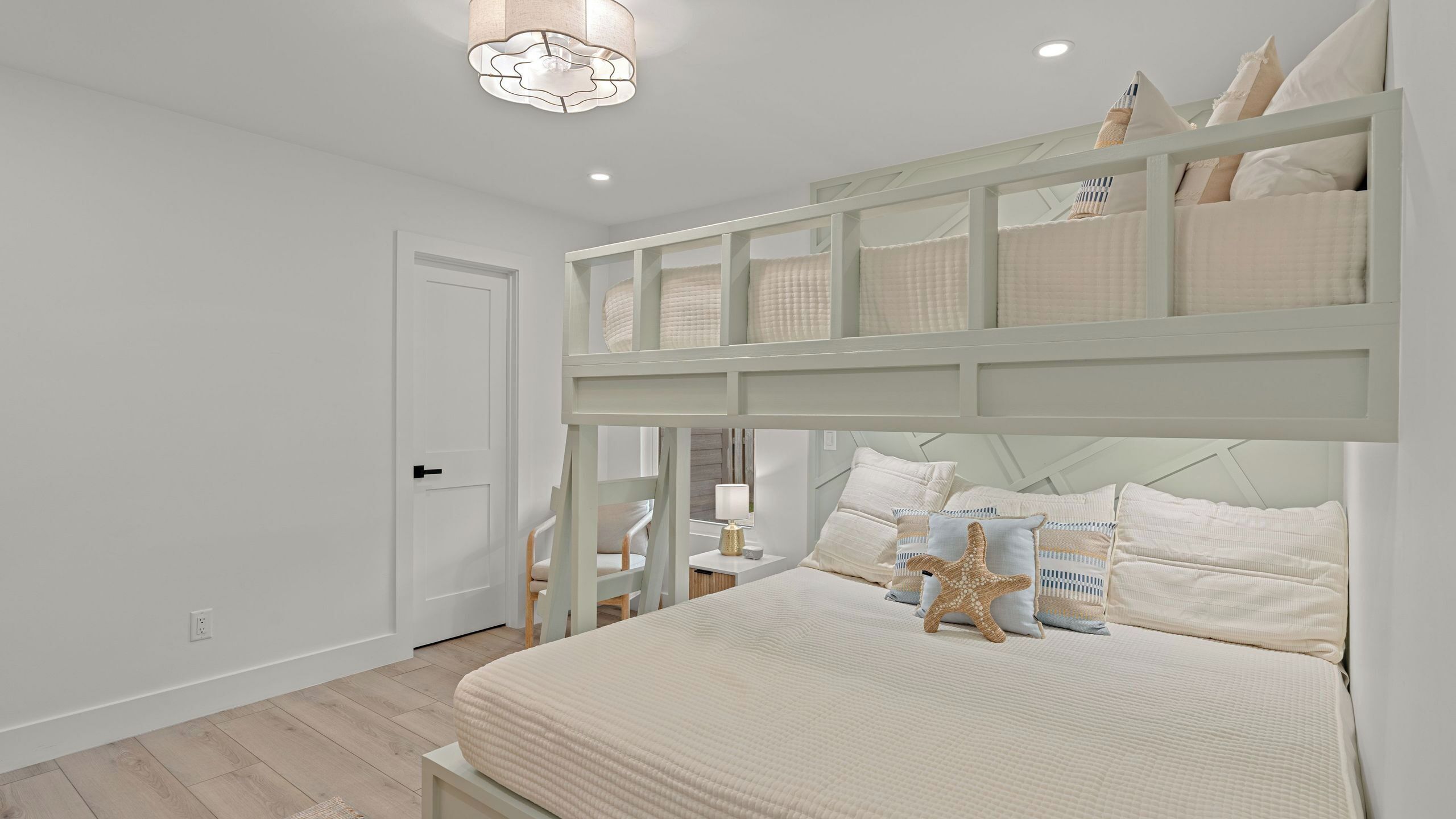 Una camera da letto con un letto a castello, un comodino, una lampada e una decorazione a forma di stella marina.