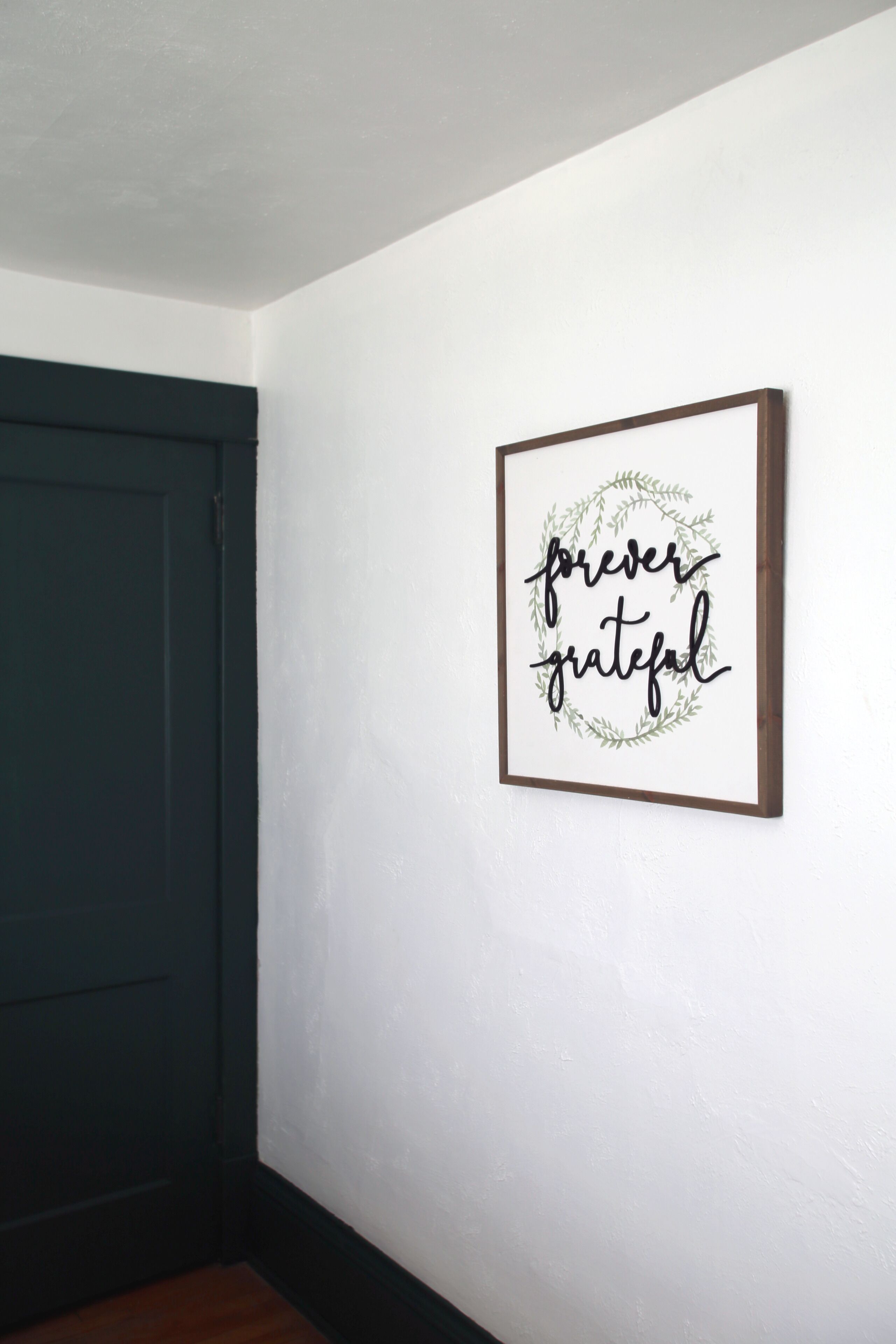 Un letrero enmarcado con la inscripción 'forever grateful' sobre una pared blanca.