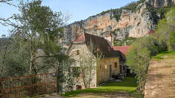 A stone building with a red roof, surrounded by greenery and a cliff. - Beautiful home in Sauliac-Sur-Célé with WiFi (Sauliac-Sur-Célé)