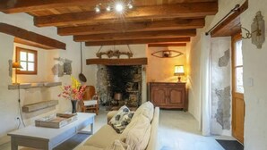 A rustic interior with exposed wooden beams, a stone fireplace, a sofa, a table with books, and a lamp. - Beautiful home in Sauliac-Sur-Célé with WiFi (Sauliac-Sur-Célé)