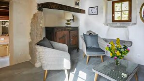 A room with a wicker sofa, a grey armchair, a small table with a vase of flowers, and a wooden cabinet. - Beautiful home in Sauliac-Sur-Célé with WiFi (Sauliac-Sur-Célé)