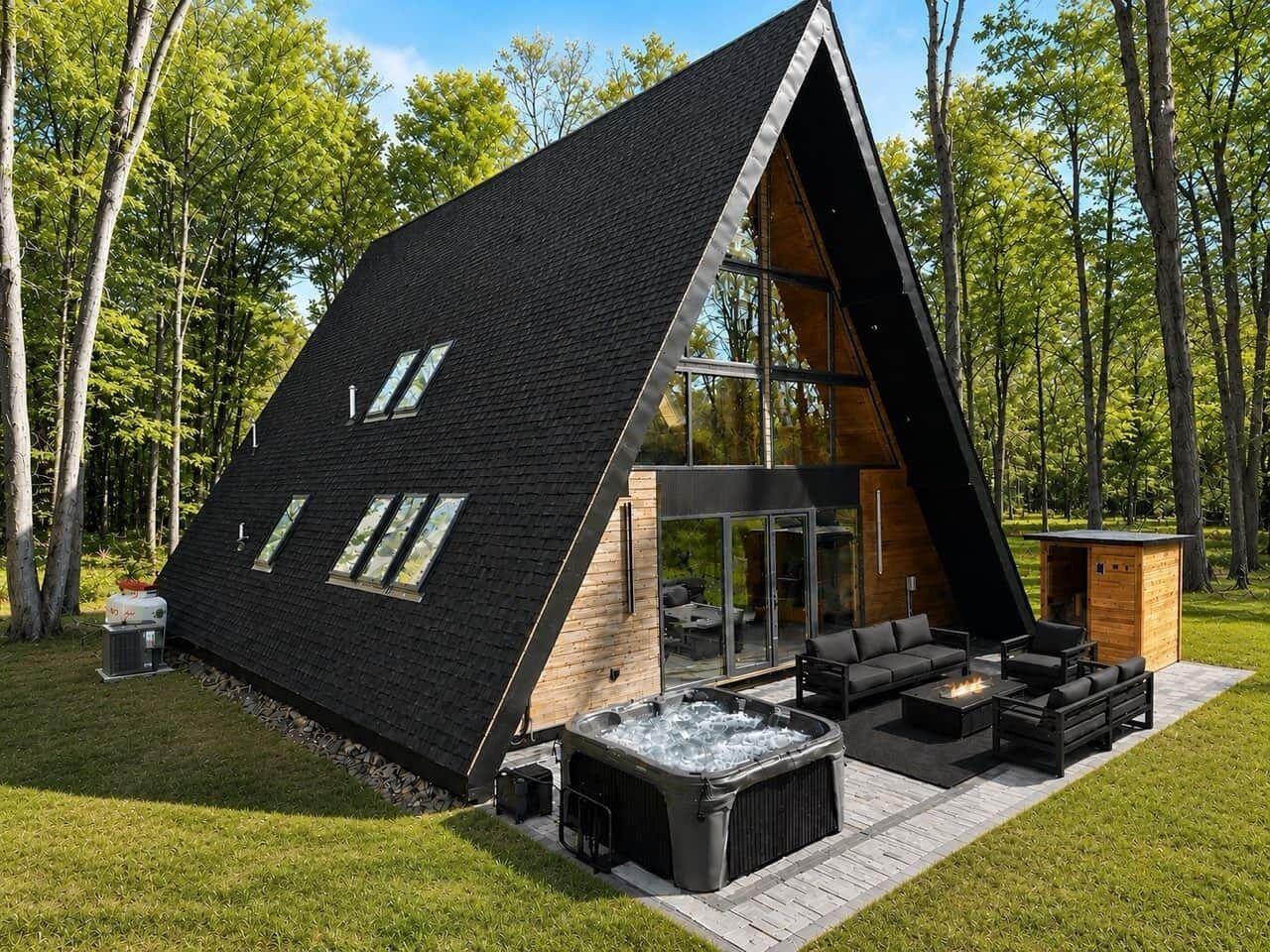 A modern, triangular-shaped building with a hot tub, outdoor seating, and a glass door entrance.