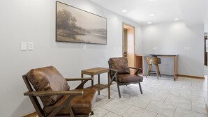 Un interior moderno con dos sillones de cuero, una mesita de madera y un cuadro en la pared.