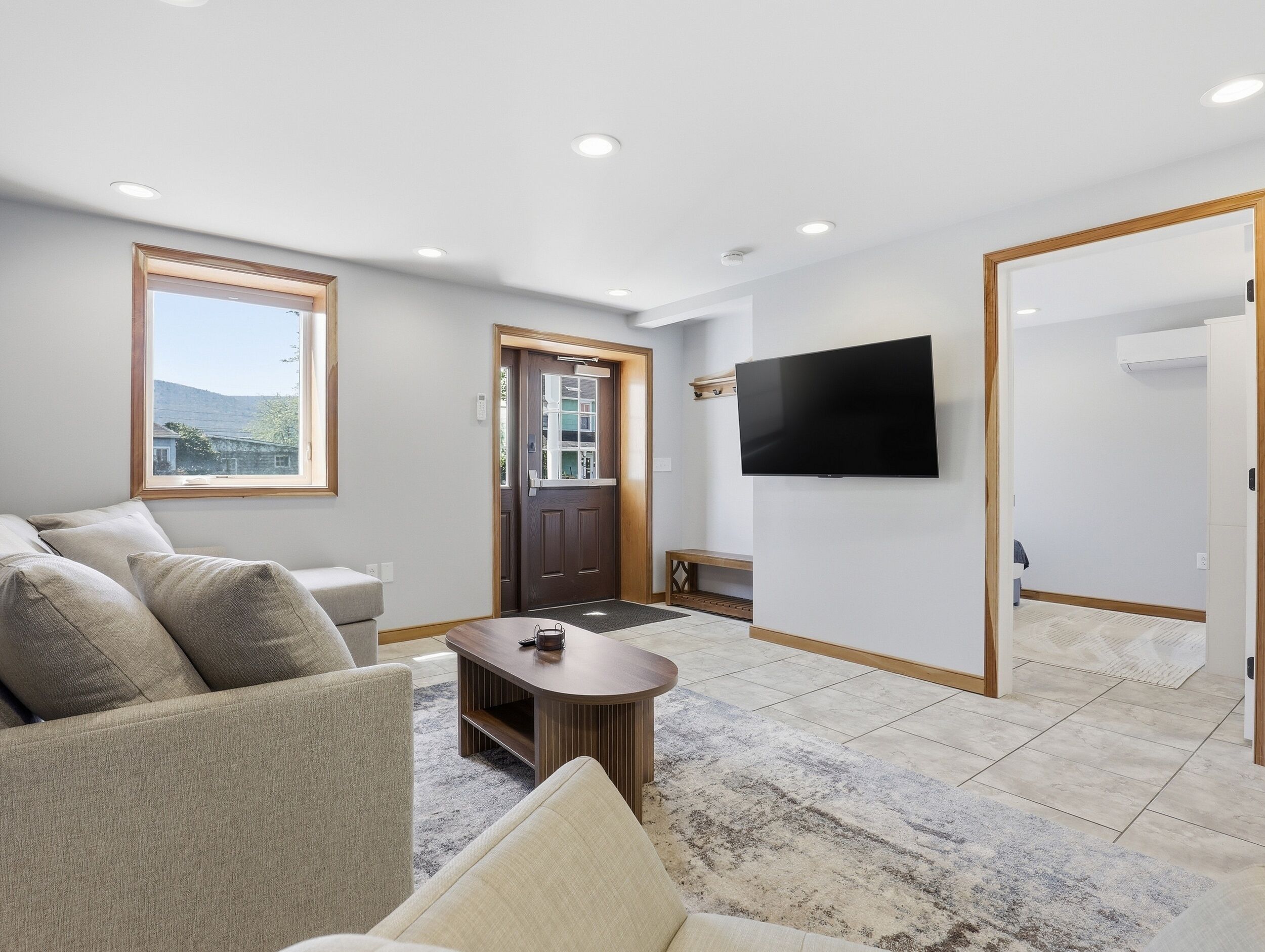 A modern living room with a sofa, coffee table, and a TV mounted on the wall.