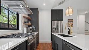 Una cocina moderna con un refrigerador de acero inoxidable, horno empotrado y estufa a gas.