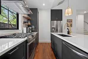 A modern kitchen with a stainless steel refrigerator, a built-in oven, and a gas stove. - Zilker Modern + Cowboy Pool - Haven! (Austin)