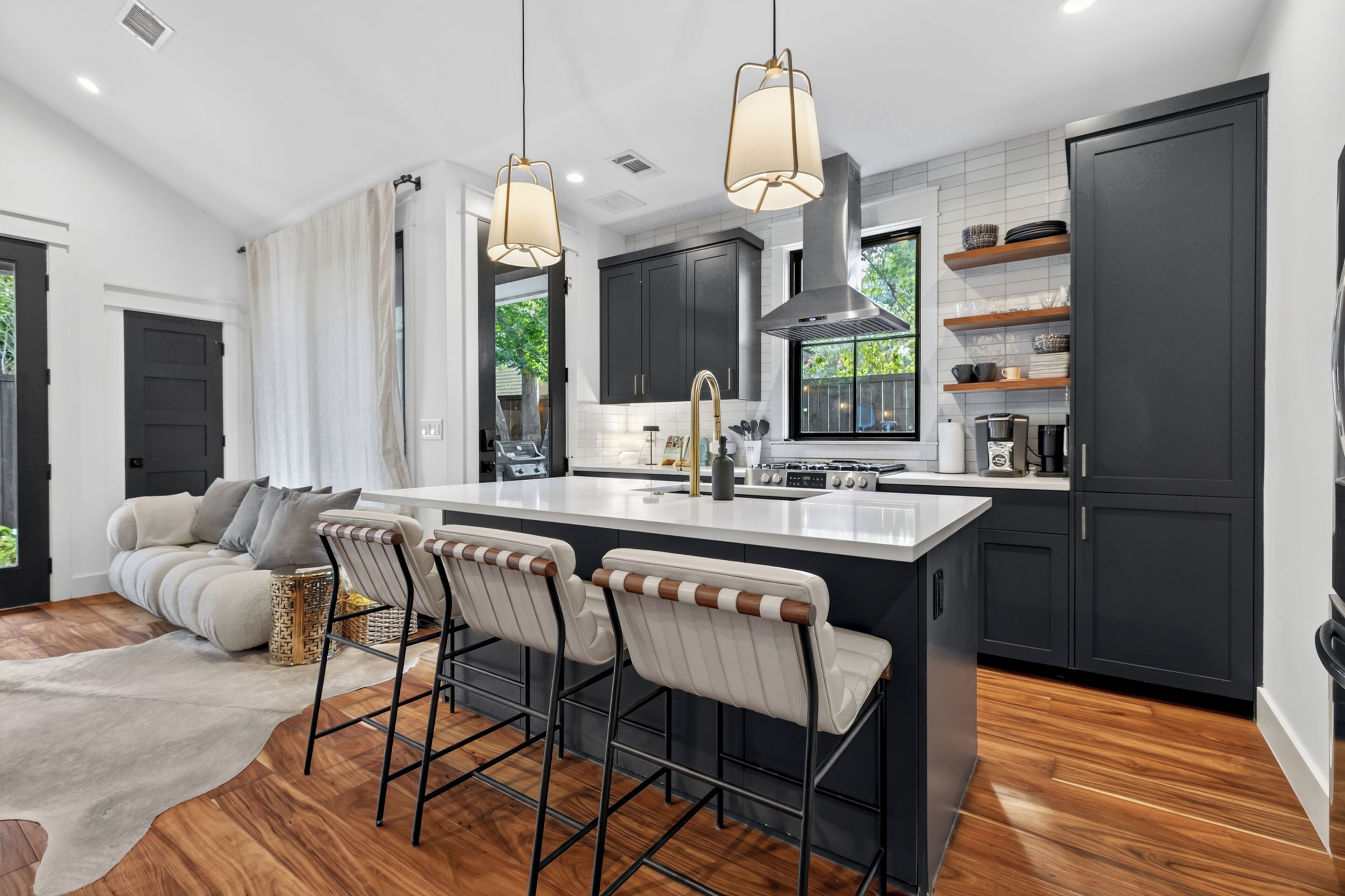 A modern kitchen with a central island, bar stools, and pendant lighting.