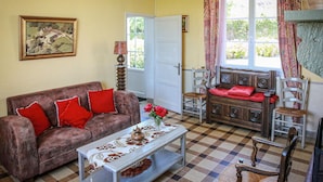 Un salón con un sofá, sillones, una mesa de centro y un cuadro en la pared.