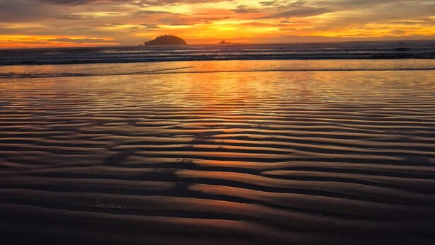 Uma praia com ondas e um pôr do sol.
