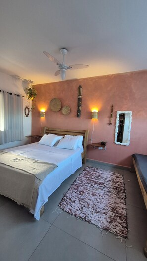 Ein Schlafzimmer mit einem Bett, einem Deckenventilator, Wandleuchten, einem Spiegel und einem Teppich.