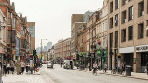 A busy urban street with pedestrians, cyclists, and vehicles. - Bright Spacious 1BR Flat in Vibrant Dalston (London)