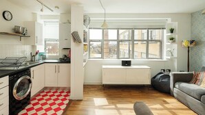 A modern apartment with a kitchen, living area, and large windows. - Bright Spacious 1BR Flat in Vibrant Dalston (London)
