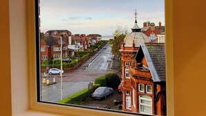 Vista a través de una ventana de una calle residencial con casas, una carretera y un farol.