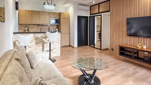 A modern living room with a sofa, a glass coffee table, a kitchen area with a microwave, and a TV mounted on the wall. - Stunning apartment in Marseille with WiFi (Marseille)