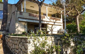A two-story building with a balcony, stone wall, and surrounding vegetation. - Nice home in Carry le rouet with house sea view (Carry le rouet)