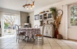 A dining area with a table, chairs, a chandelier, a clock, and a view through a window. - 4 bedroom amazing home in Arles (Arles)