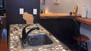 Una cocina con salpicadero de piedra, grifo negro y encimera de madera.