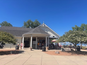A building with a covered entrance, outdoor seating, and a sign indicating a beachside menu.