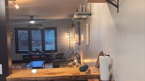 Una cocina con encimera de madera, una silla, una mesa de comedor y un ventilador de techo.