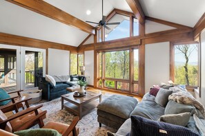 Ein geräumiges Wohnzimmer mit hohen Decken, großen Fenstern und Holzvertäfelung.