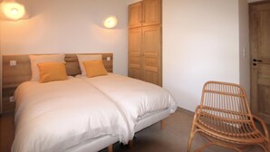 Een tweepersoonsbed met witte lakens, een houten hoofdbord en twee wandlampen.