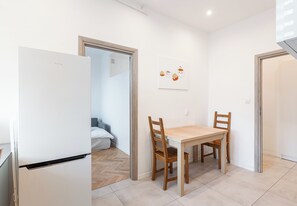 Une cuisine moderne avec un réfrigérateur blanc, une table en bois et des chaises.