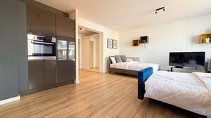 Et moderne hotelværelse med tekøkken, seng, TV og trægulv.